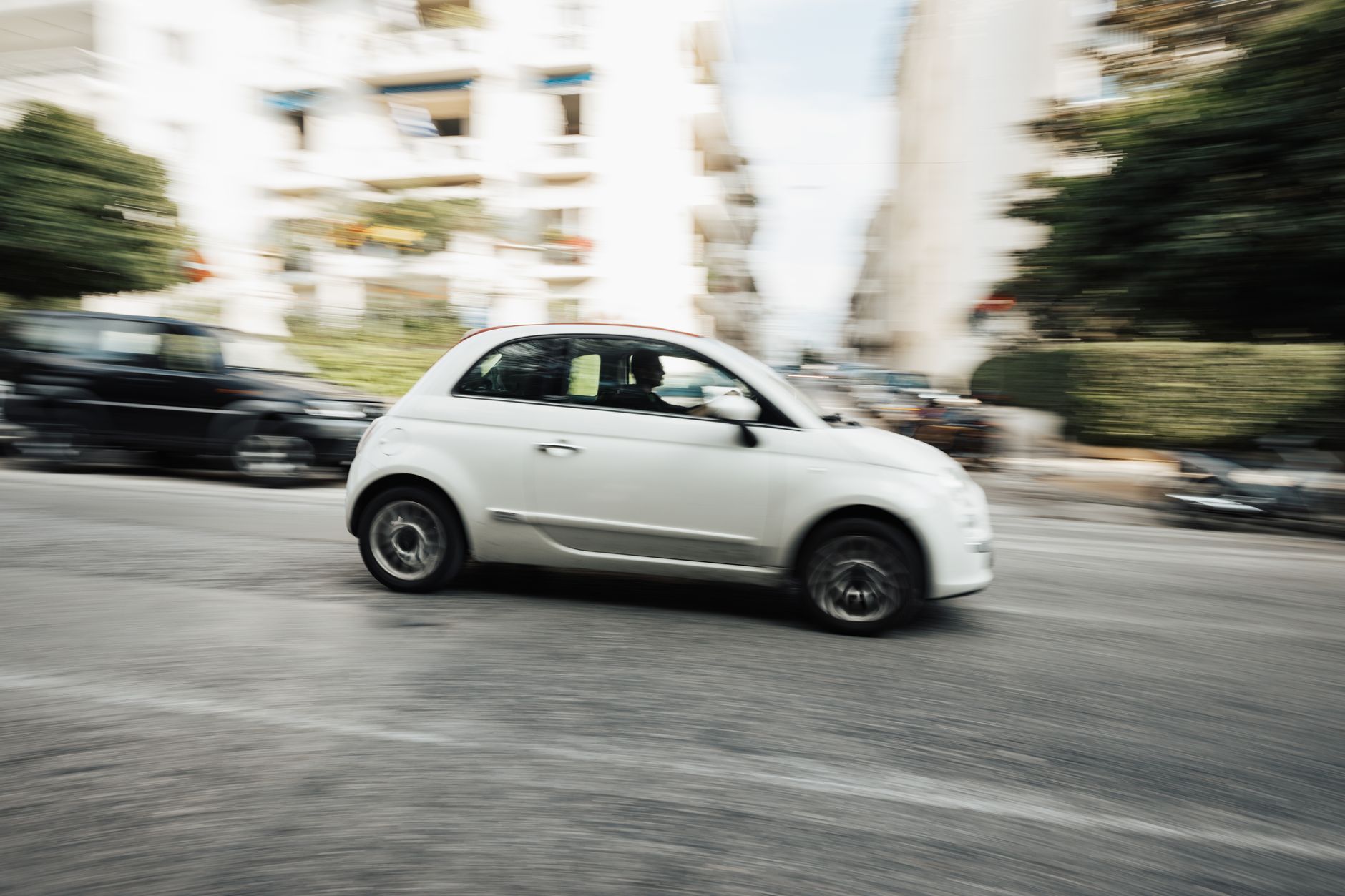 Białe miejskie auto Mitsubishi jedzie szybko ulicą z efektem rozmycia ruchu