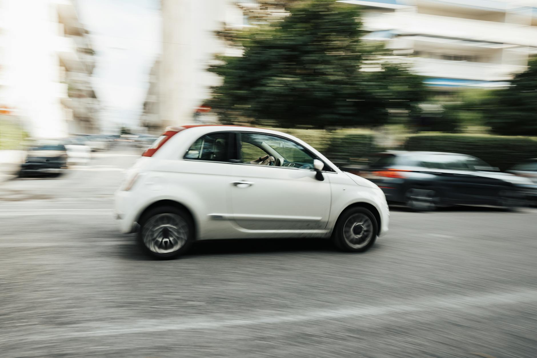 Białe Mitsubishi jadące szybko ulicą miasta z rozmytym tłem