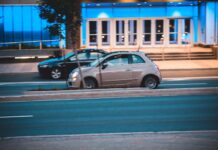 Małe miejskie auto na ulicy obok nowoczesnego, niebiesko podświetlonego budynku