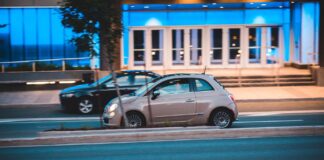Małe miejskie auto na ulicy obok nowoczesnego, niebiesko podświetlonego budynku