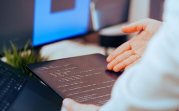 Jak zacząć przygodę ze sztuczną inteligencją: praktyczny przewodnik dla początkujących programistów Programista analizuje kod na tablecie w nowoczesnym biurze