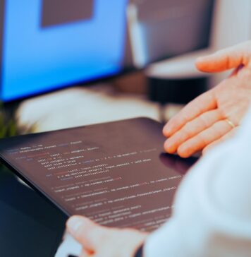 Programista analizuje kod na tablecie w nowoczesnym biurze