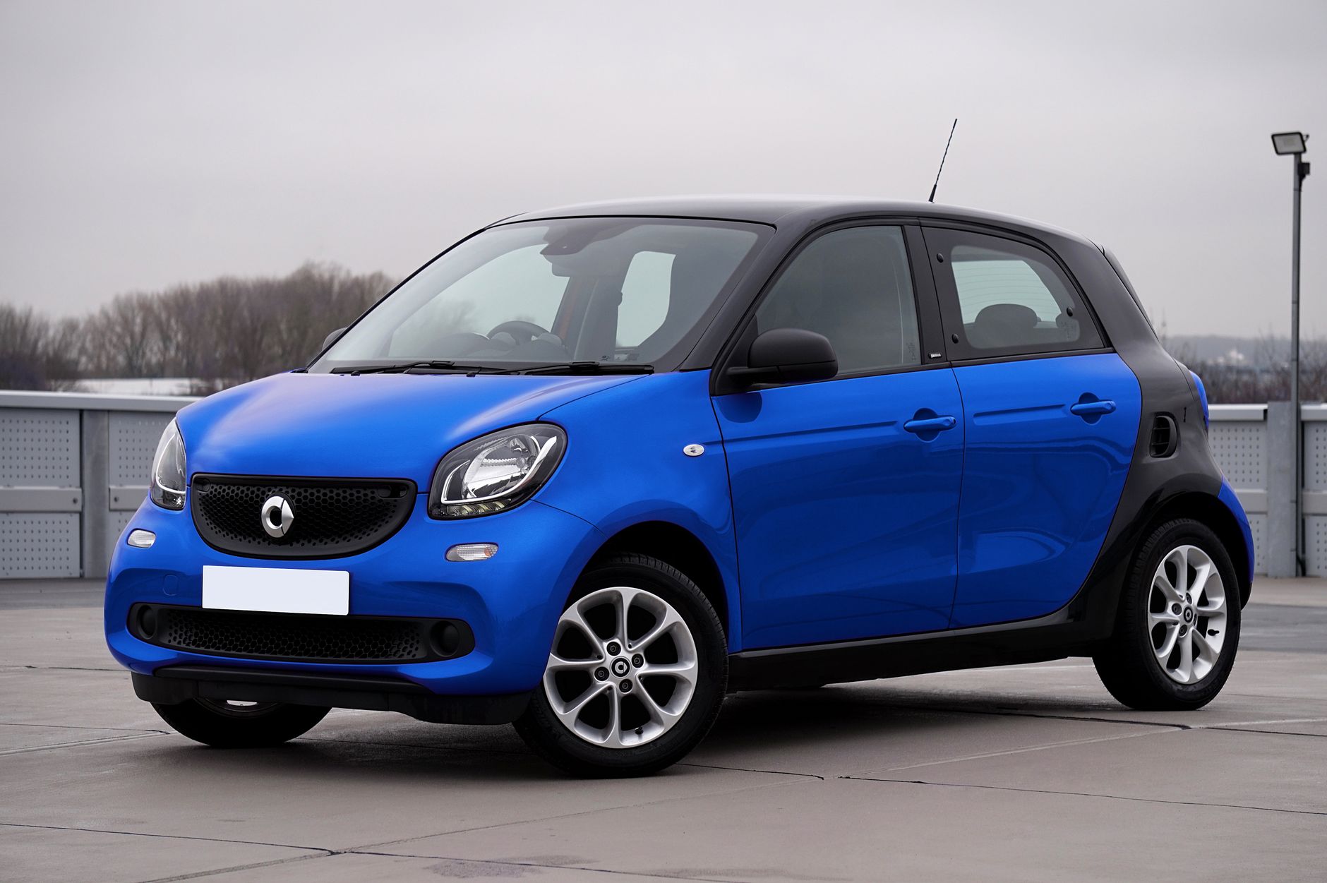 Niebieski Smart Forfour zaparkowany przy miejskiej ulicy Niebieski Smart Forfour zaparkowany przy miejskiej ulicy