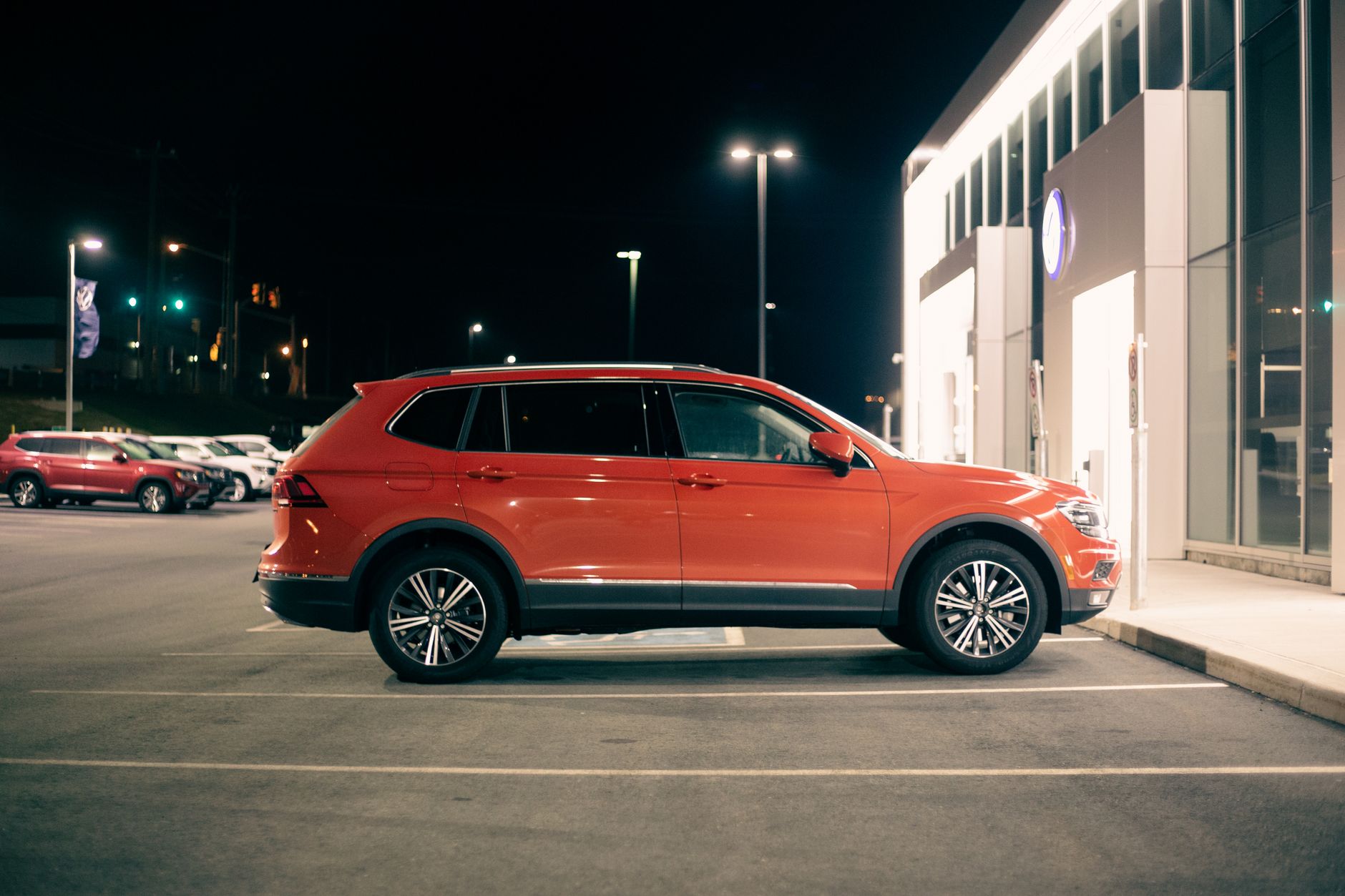 Czerwony SUV terenowy zaparkowany nocą przy wejściu do sklepu