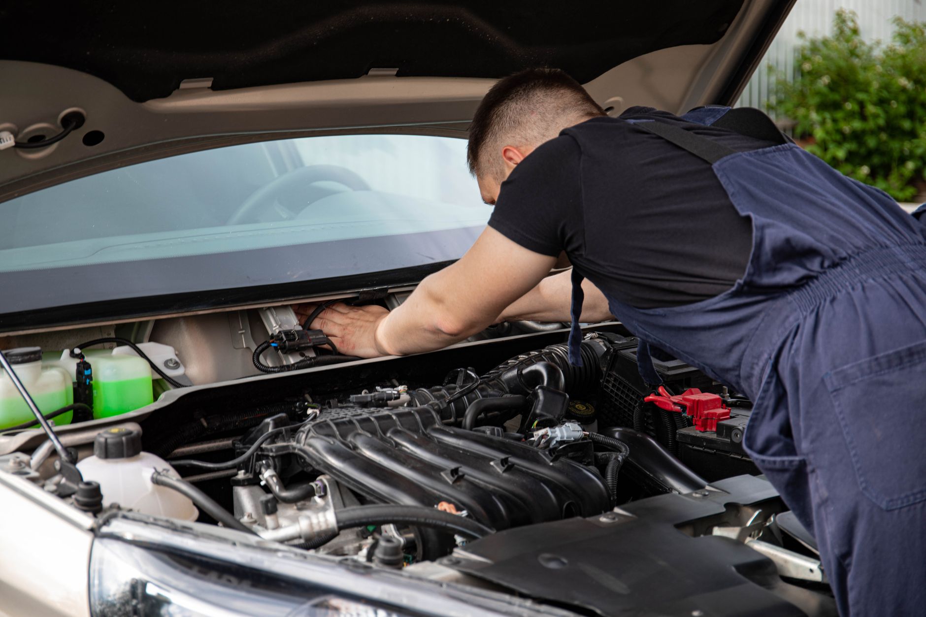 Mechanik serwisuje silnik auta, zbliżenie na dłonie i podzespoły