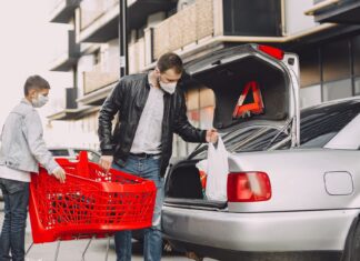 Ojciec z synem pakują zakupy do bagażnika Nissana na parkingu