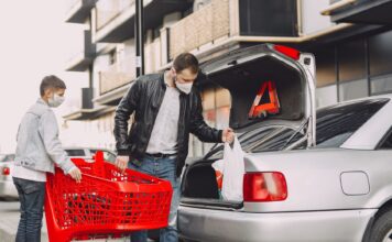 Ojciec z synem pakują zakupy do bagażnika Nissana na parkingu