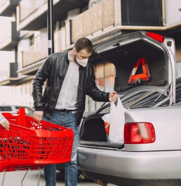 Ojciec z synem pakują zakupy do bagażnika Nissana na parkingu
