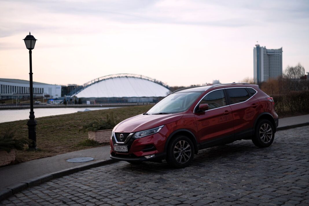 Czerwony Nissan Qashqai na brukowanej ulicy w Czerwony Nissan Qashqai na brukowanej ulicy w